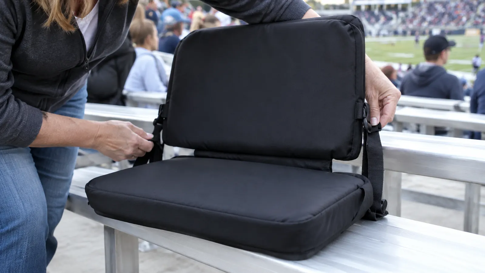 Close view of the stadium seat's padded backrest and seat base strapped to a bleacher bench