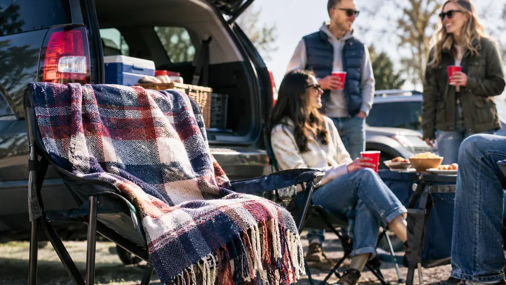 The blanket draped over a tailgate chair next to an open SUV trunk