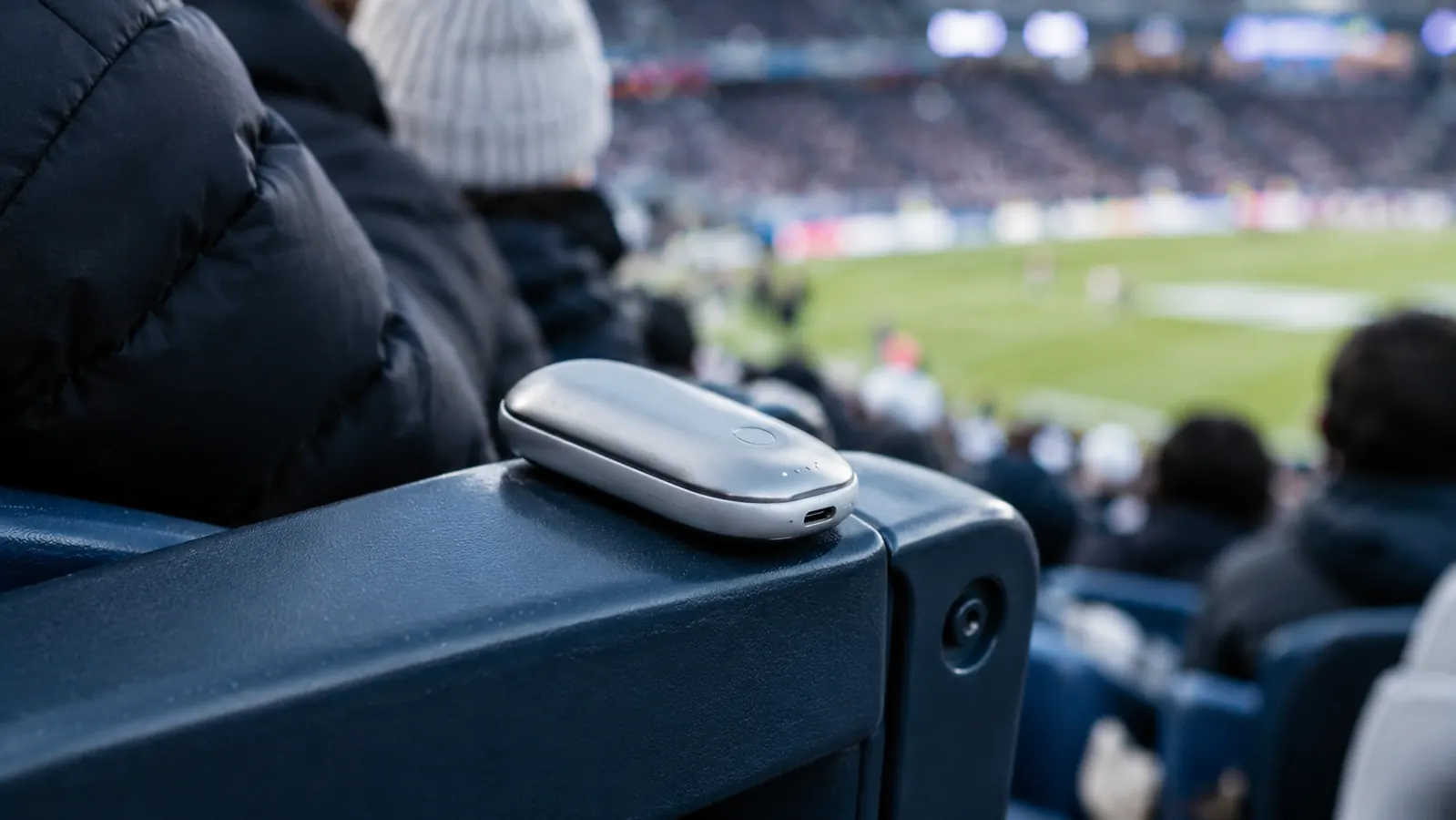 a hand warmer resting on the armrest of a stadium seat during a cold game